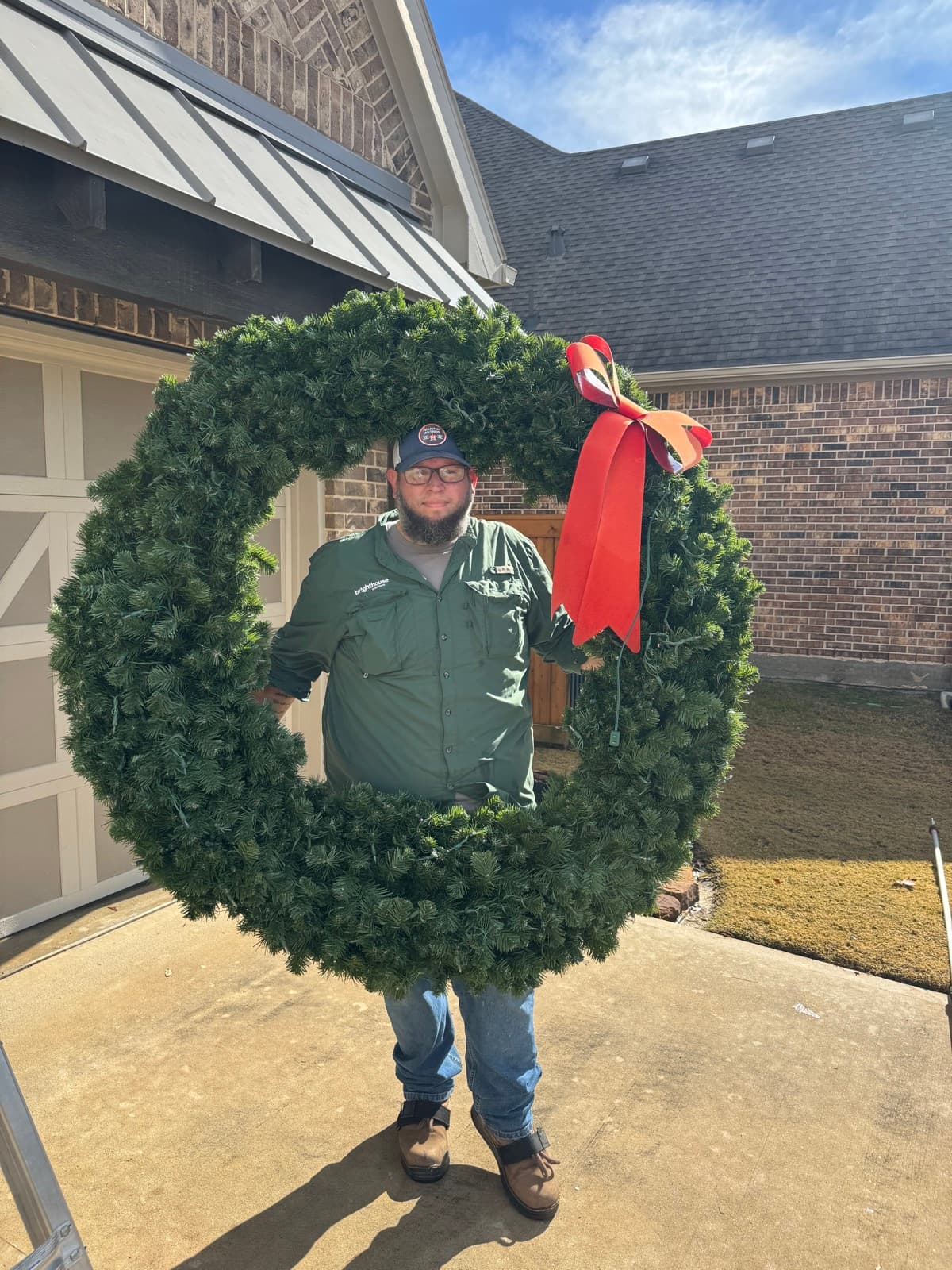Trey holding a giant Christmas wreath at an install